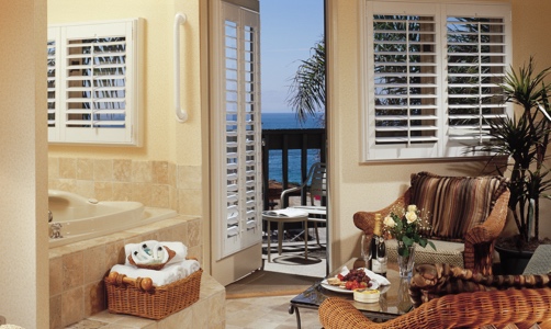 Plantation shutters on casement windows in a lakefront house.